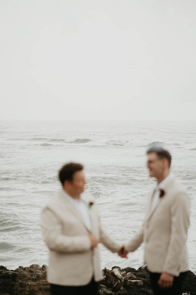 Two grooms holding hands at their Oregon Coast elopement