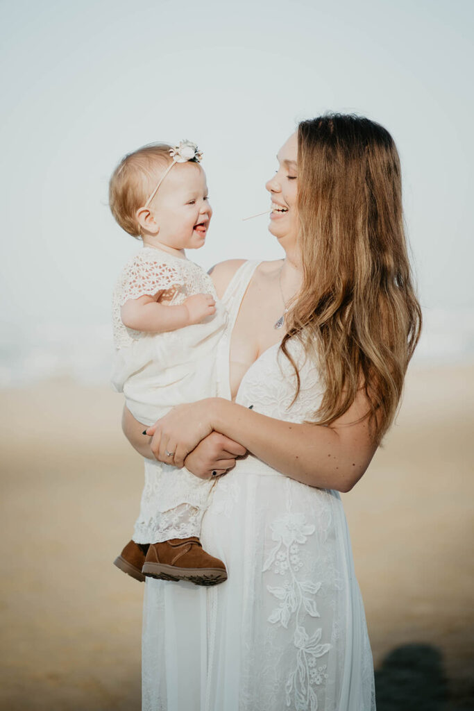 Bride and daughter laugh during intimate beach wedding portraits