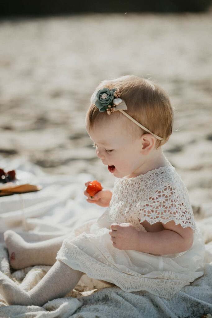 Daughter eating strawberry during intimate beach wedding picnic
