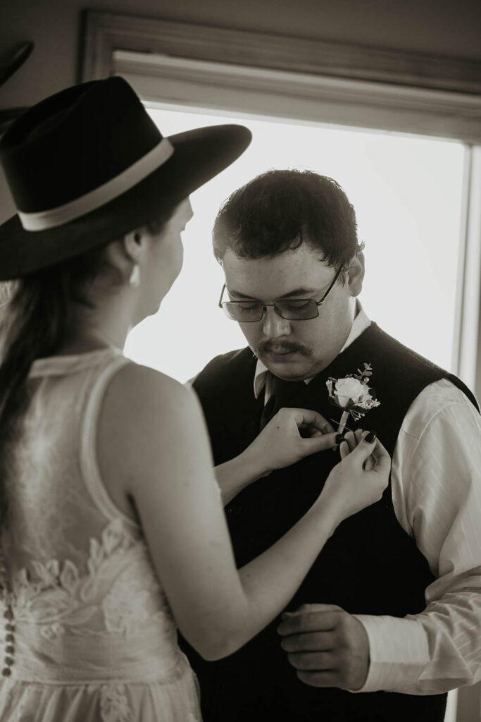 Bride helping groom with boutonnier 
