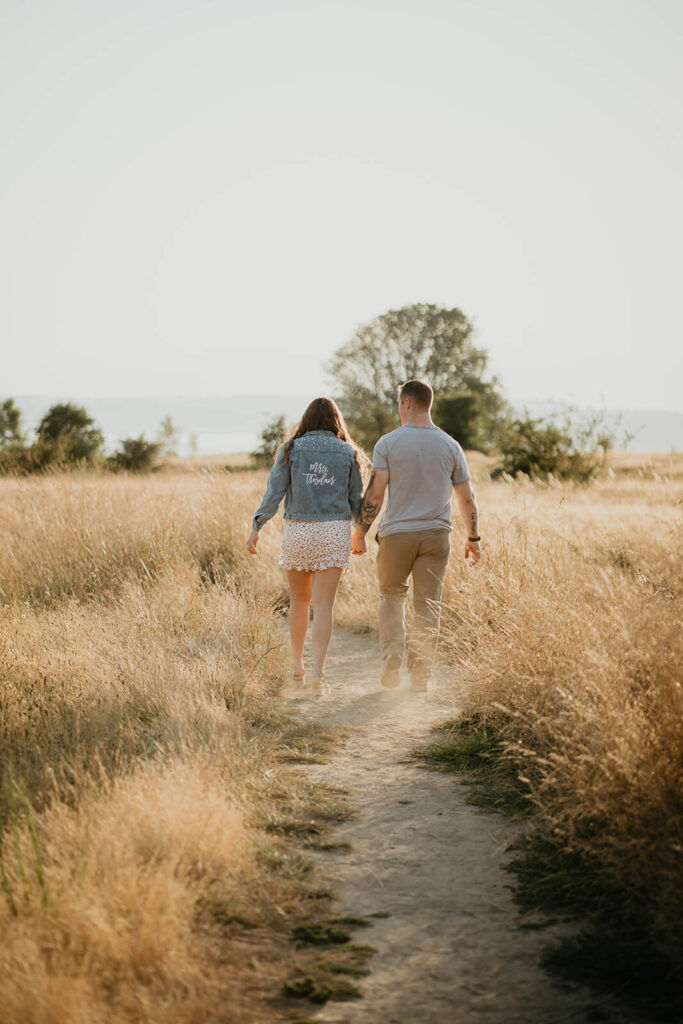 Couple holding hands while walking around Discover Park for their Seattle engagement photos