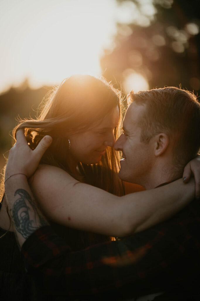 Couple sitting on the trail hugging during sunset engagement photos at Discovery Park