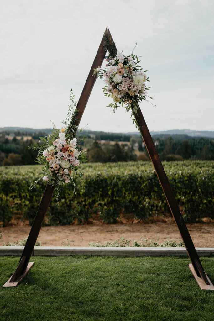 Wood wedding arch with pastel floral arrangements 
