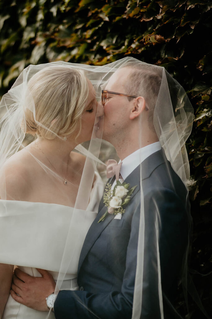 Bride and groom kiss under a veil at Ponzie Vineyards wedding