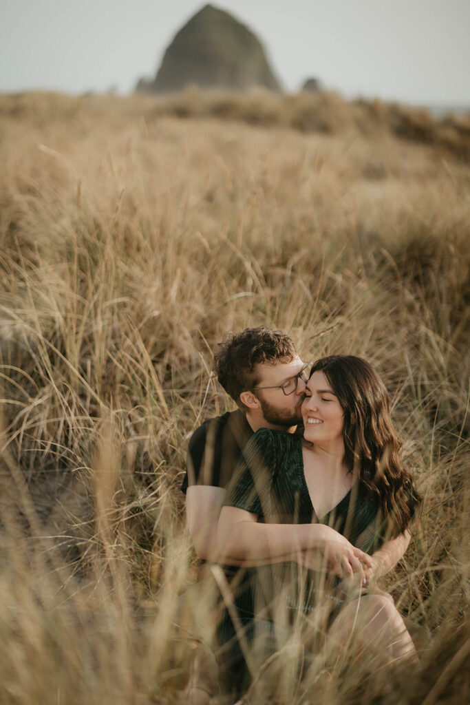 Couple sitting in the grass during their engagement photos on the beach