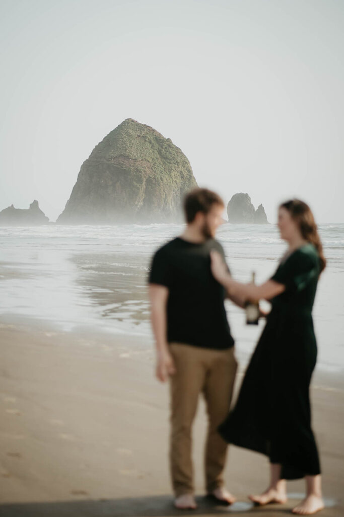 Couples popping champagne on the Cannon Beach during their beach engagement photos