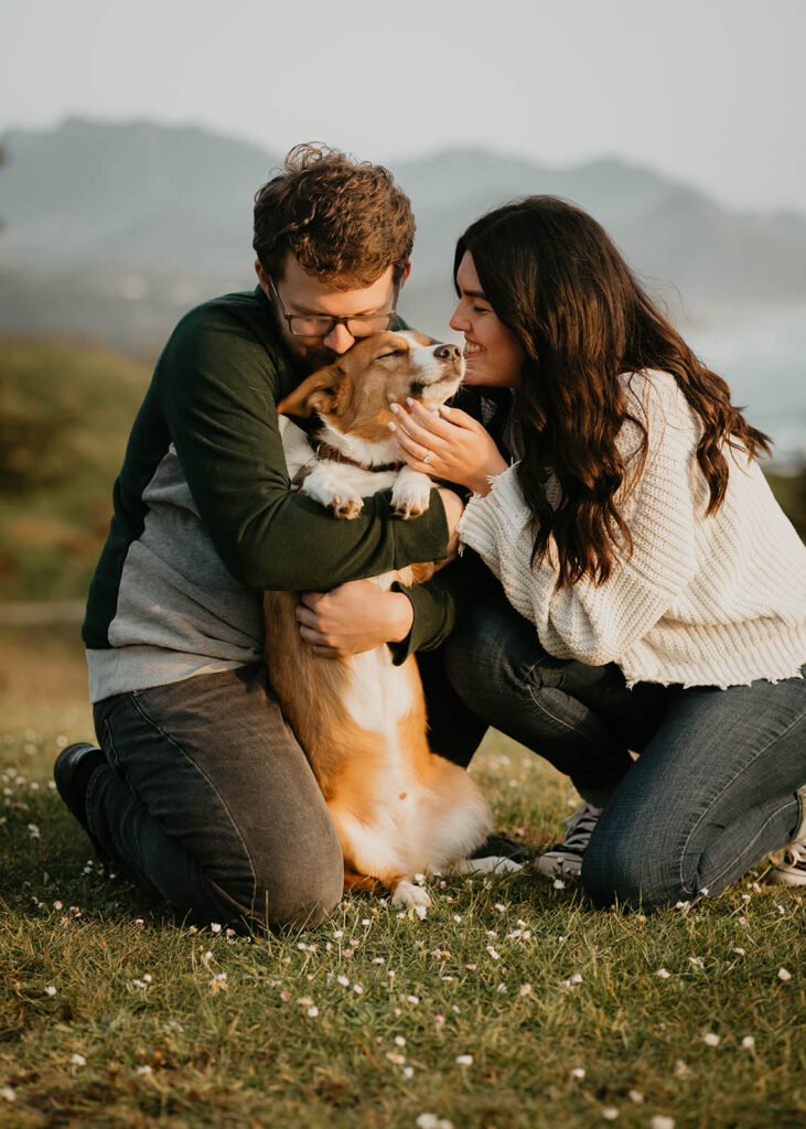 Couple kisses their dog during beach engagement photos
