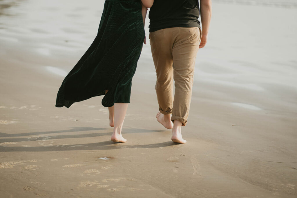 Couple walking in the sand during their beach engagement photos