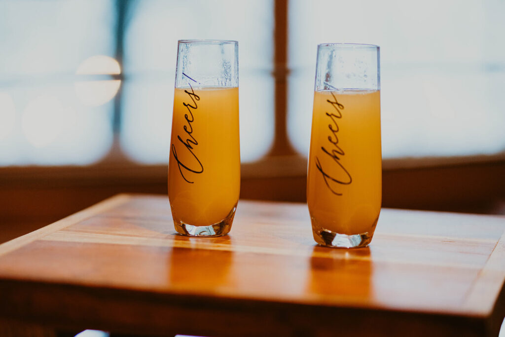 Two champagne glasses filled with mimosas 