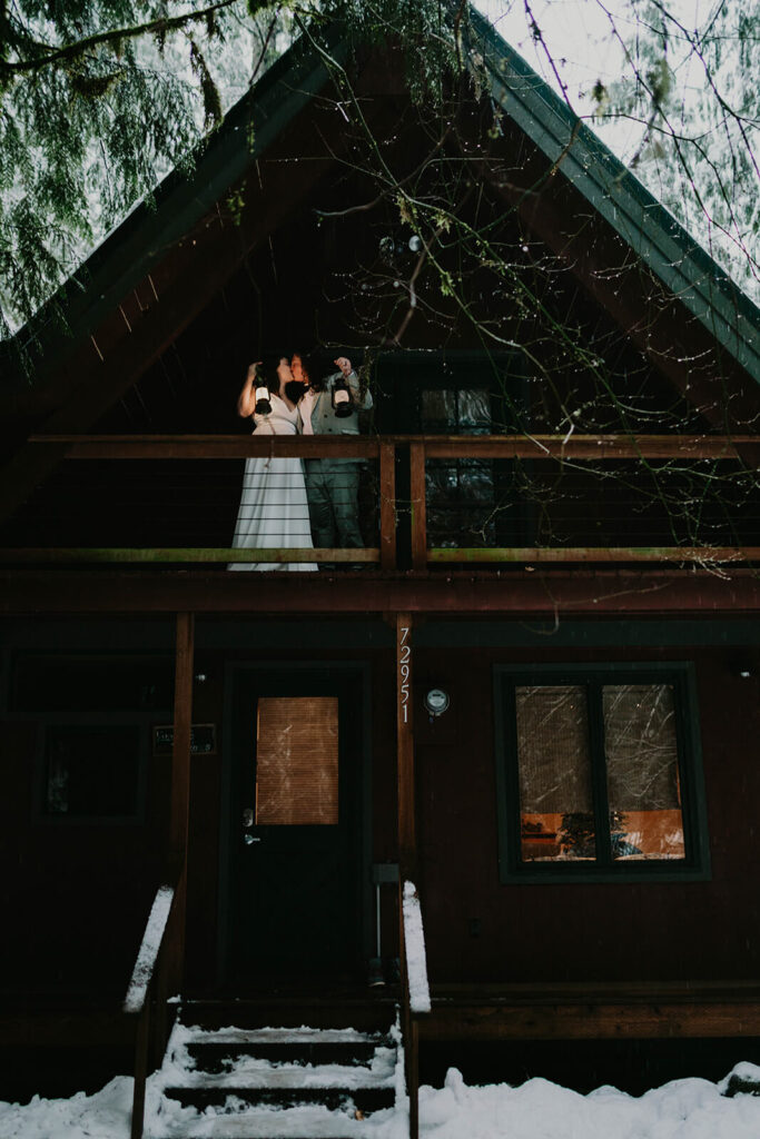 Two brides holding lanterns at their dark moody wedding cabin in Oregon