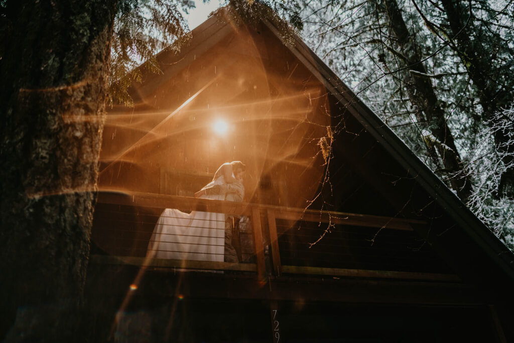 Two brides kissing at their dark moody wedding cabin in Oregon