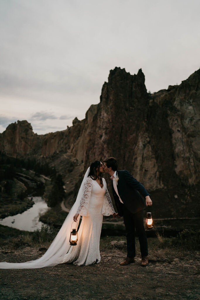 Bride and groom kissing and holding lanterns at their adventure elopement at Smith Rock State Park