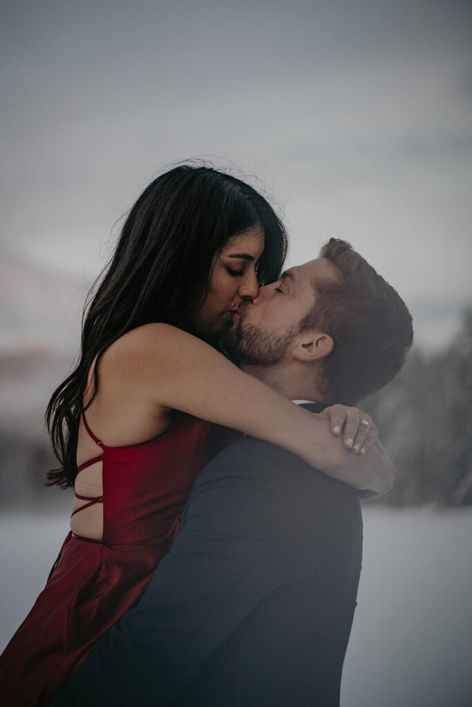 Couple kissing in the snow during winter engagement photo session