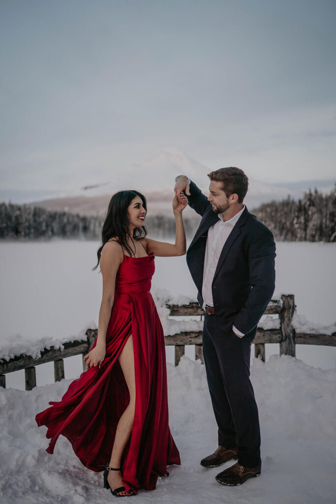 Couple dancing in the snow during winter engagement photo session