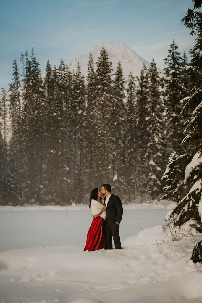 Couple kissing during engagement photos with red dress