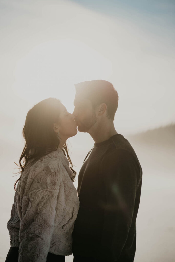 Couple kissing during snowy engagement photos in Oregon