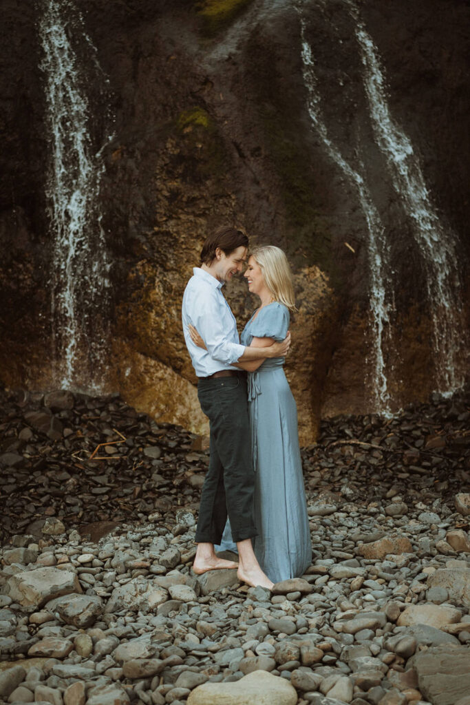 Couple holding hands in front of waterfall at Hug Point State Park