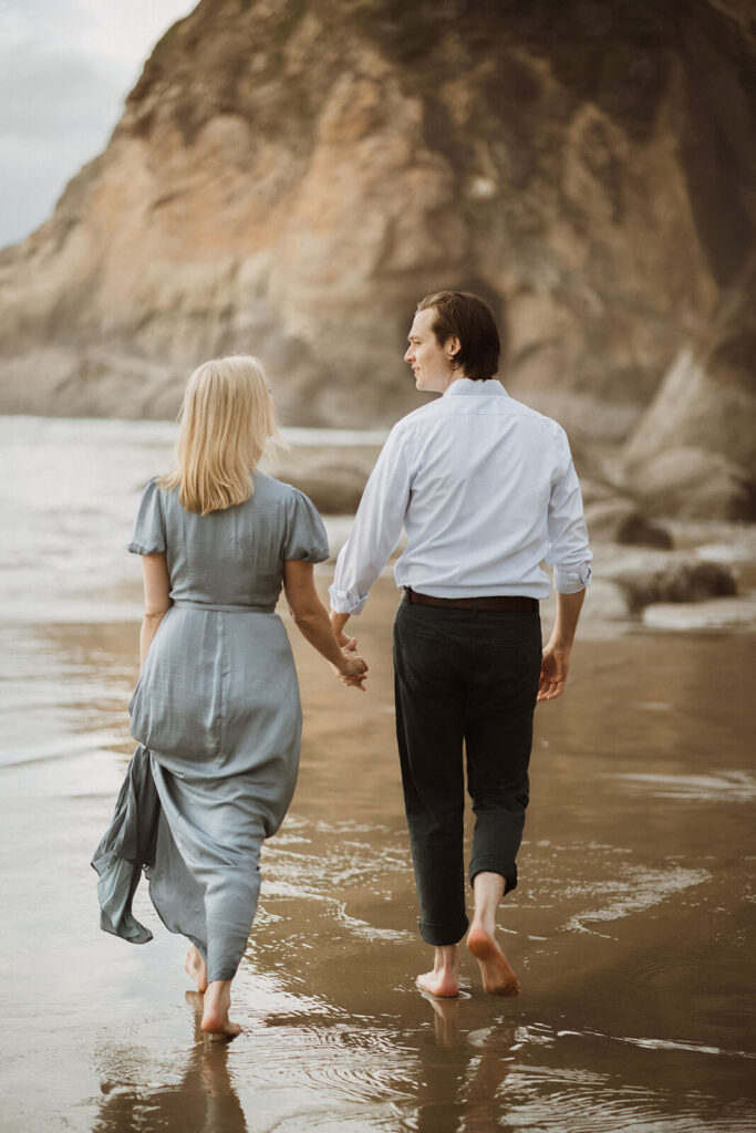 Couple holding hands while walking across the beach at Hug Point State Park