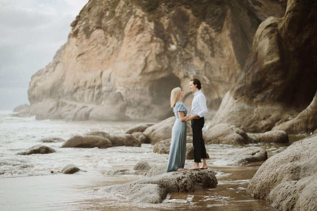 Couple holding hands at Hug Point State Park during engagement photo session
