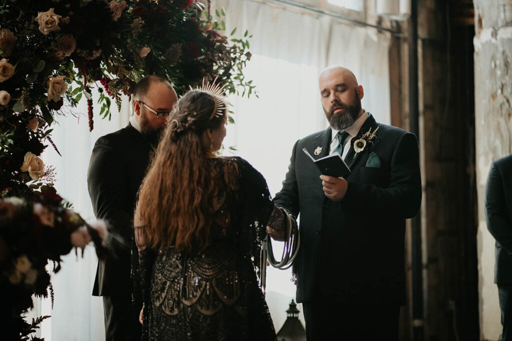 Groom reads handwritten vows at dark wedding ceremony