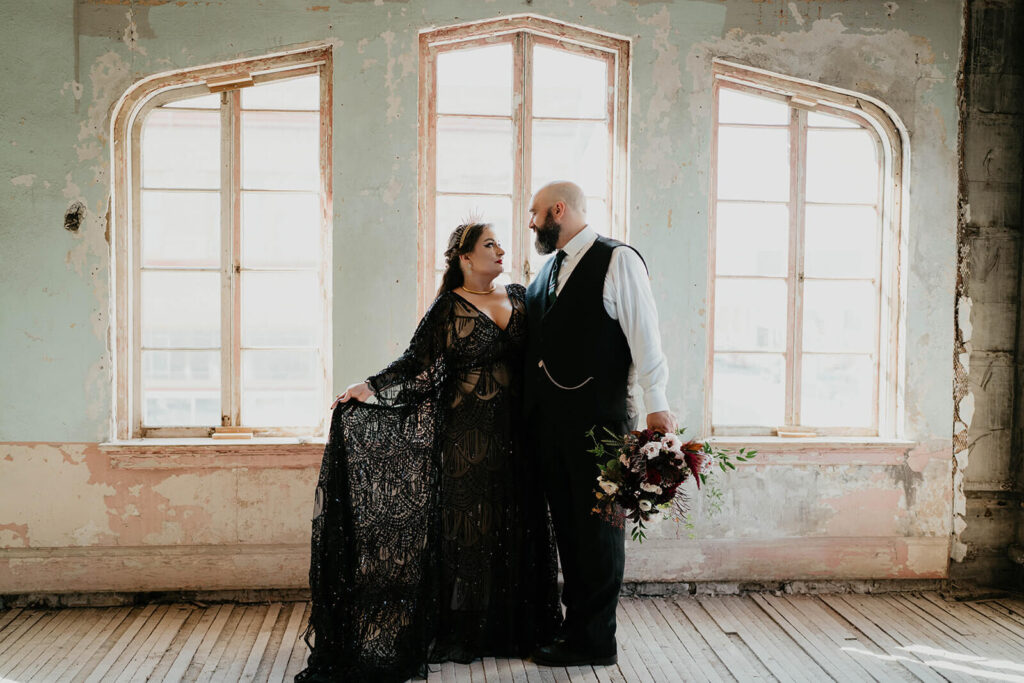 Bride wearing black lace wedding dress and groom wearing black vest and pants