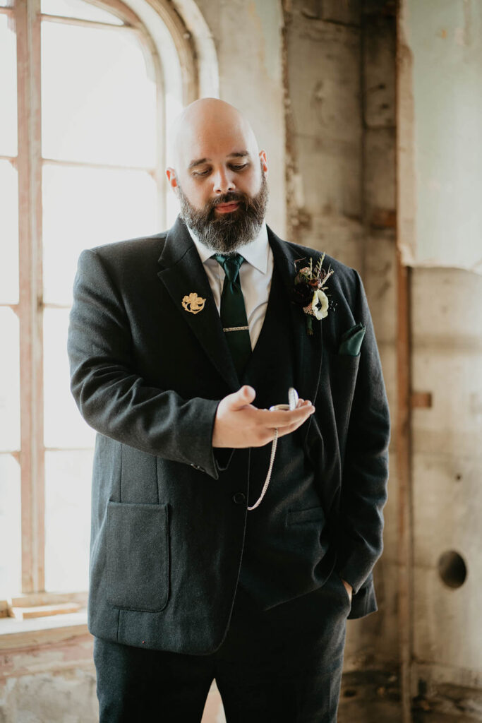 Groom wearing black suit at dark, moody fall wedding
