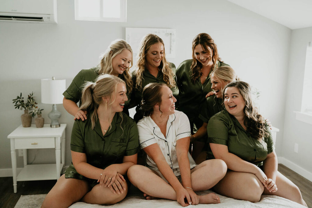 Bridemaids in green pajamas surrounding bride and laughing