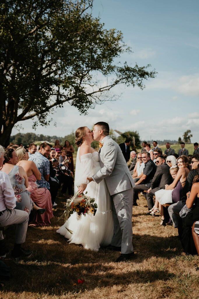 Bride and groom kiss at the end of the aisle after exiting wedding ceremony
