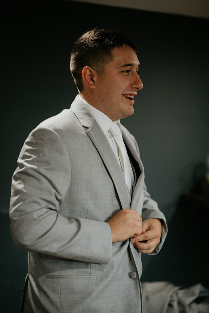 Groom buttoning gray suit 