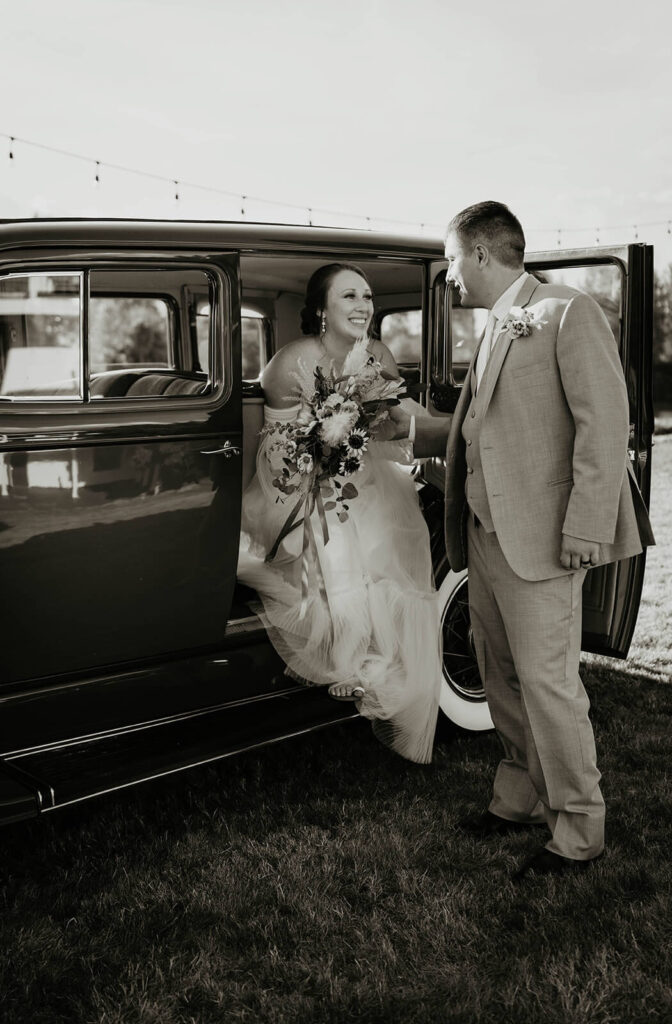Bride getting out of vintage car at Pemberton Farm wedding