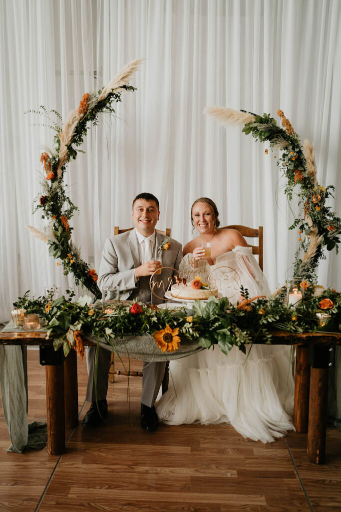 Bride and groom sitting at the head table at their romantic wedding reception