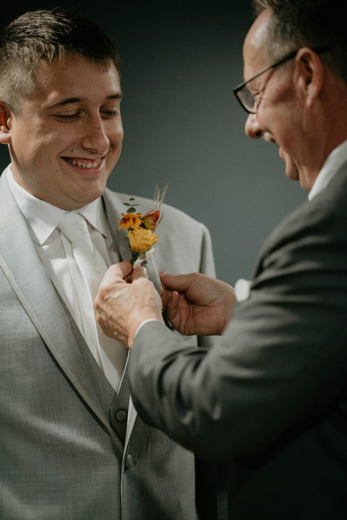Groom's father pinning on boutonniere 