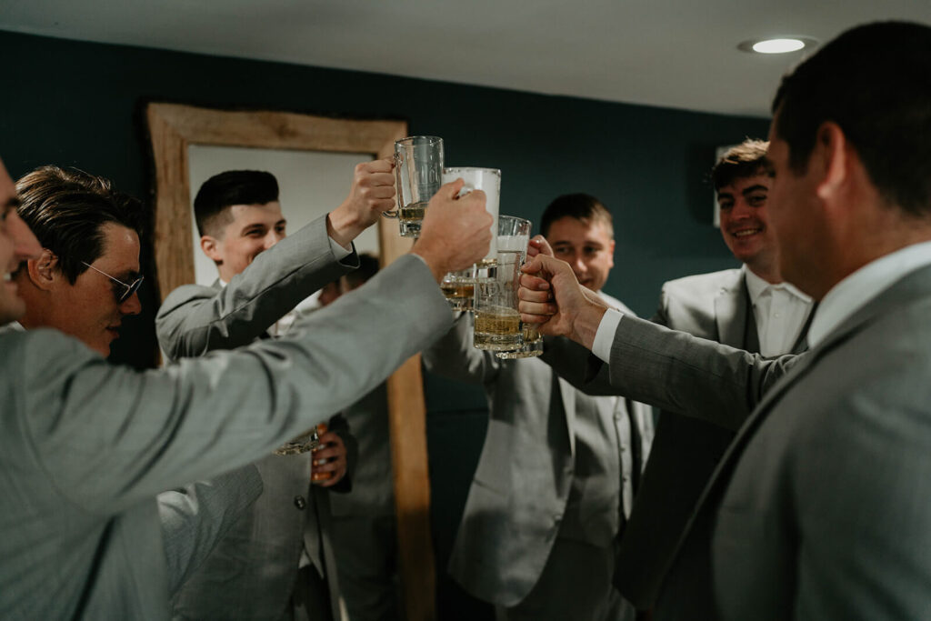 Groomsmen cheering with custom beer glasses at Pemberton Farm wedding