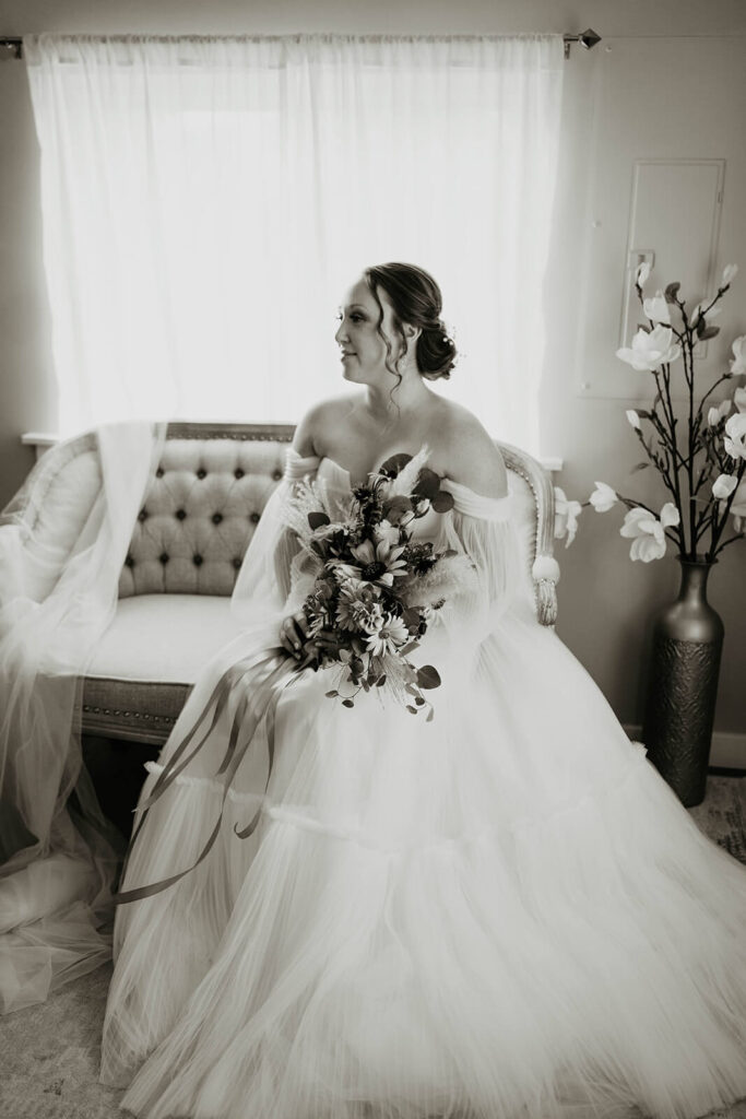 Bride sitting on a loveseat in her romantic flowy wedding dress at Pemberton Farm