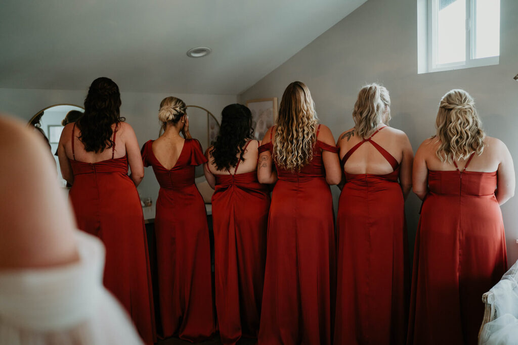 Bridesmaids wearing burnt orange dresses waiting to do first look with bride