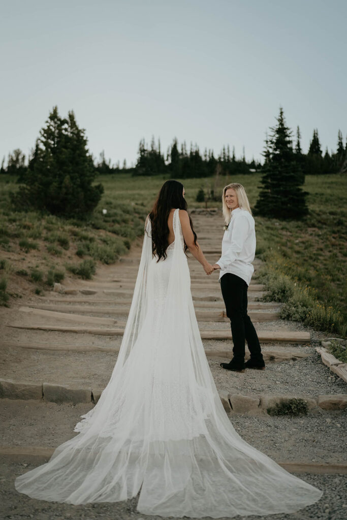 Two brides walk down a trail at Sunrise, Mt Rainier after their elopement ceremony