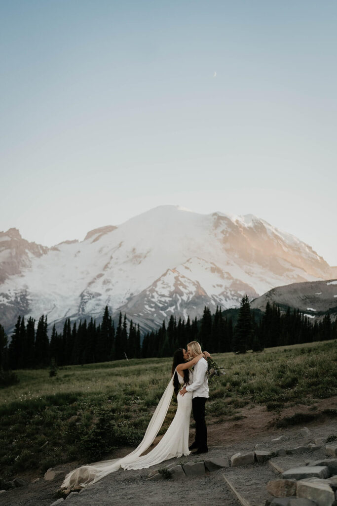 Two brides kissing in front of Mt Rainier