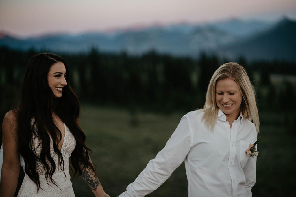 Brides hold hands while walking down a trail at Sunrise, Mt Rainier