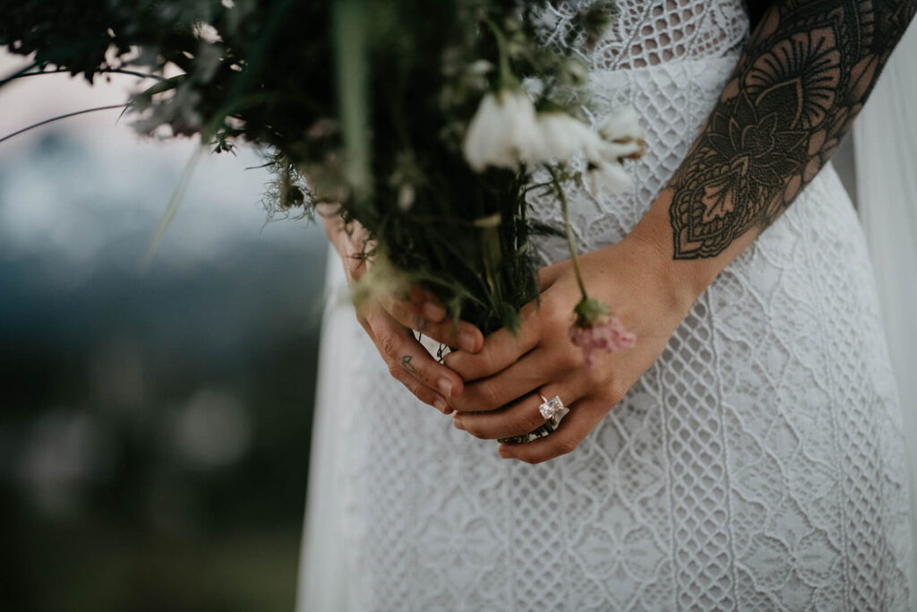 Bride holding a wildflower bouquet while wearing an emerald cut wedding ring
