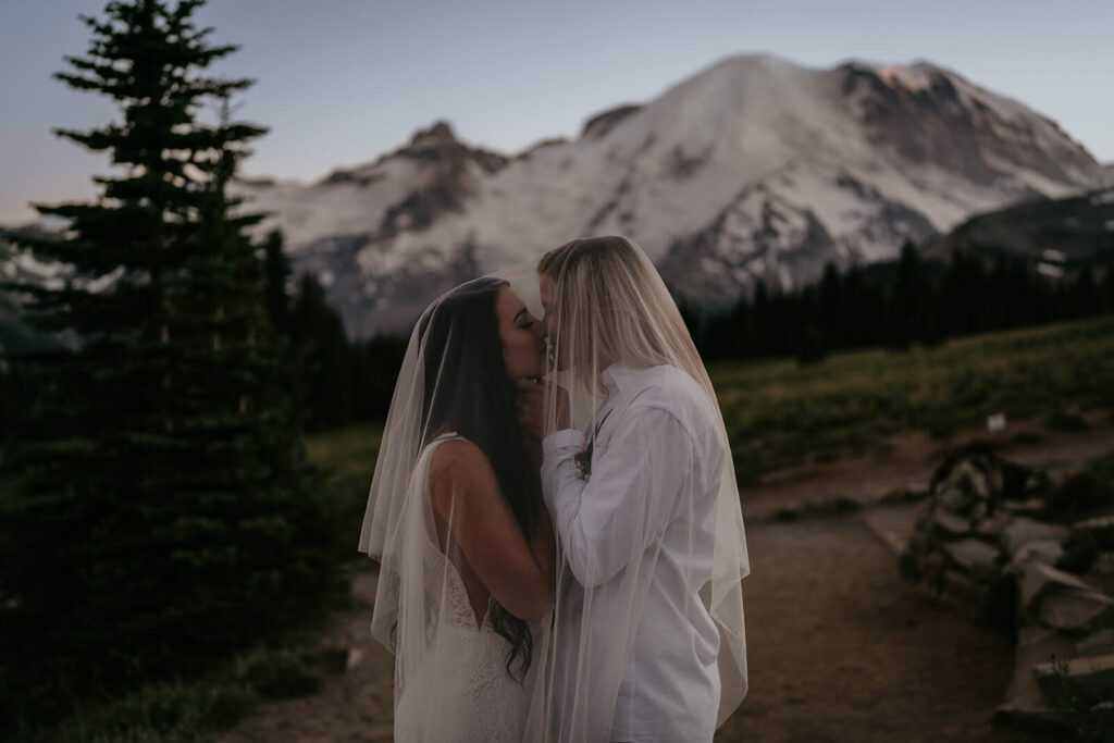 Two brides kiss under wedding veil at Mt Rainier