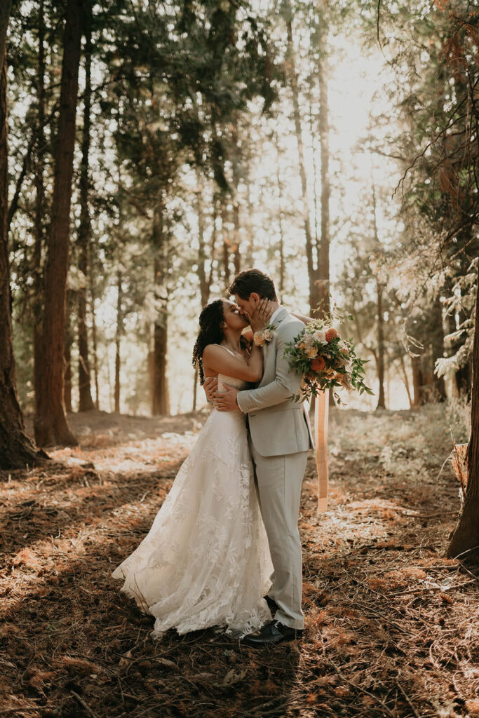 Bride and groom kiss in the forest after their first look at woodland themed wedding