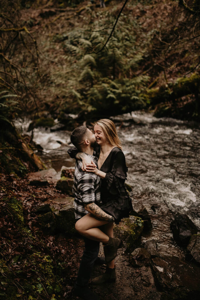 Couple laughing and kissing by the river at Latourell Falls