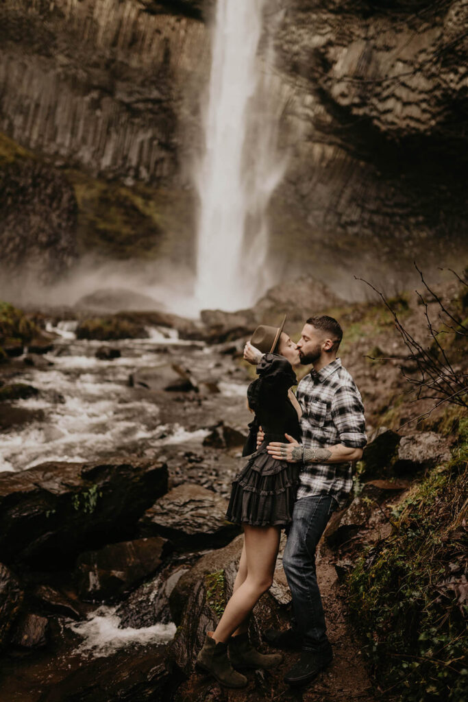 Man and woman kissing in front of Latourell Falls during their winter engagement photos in Oregon