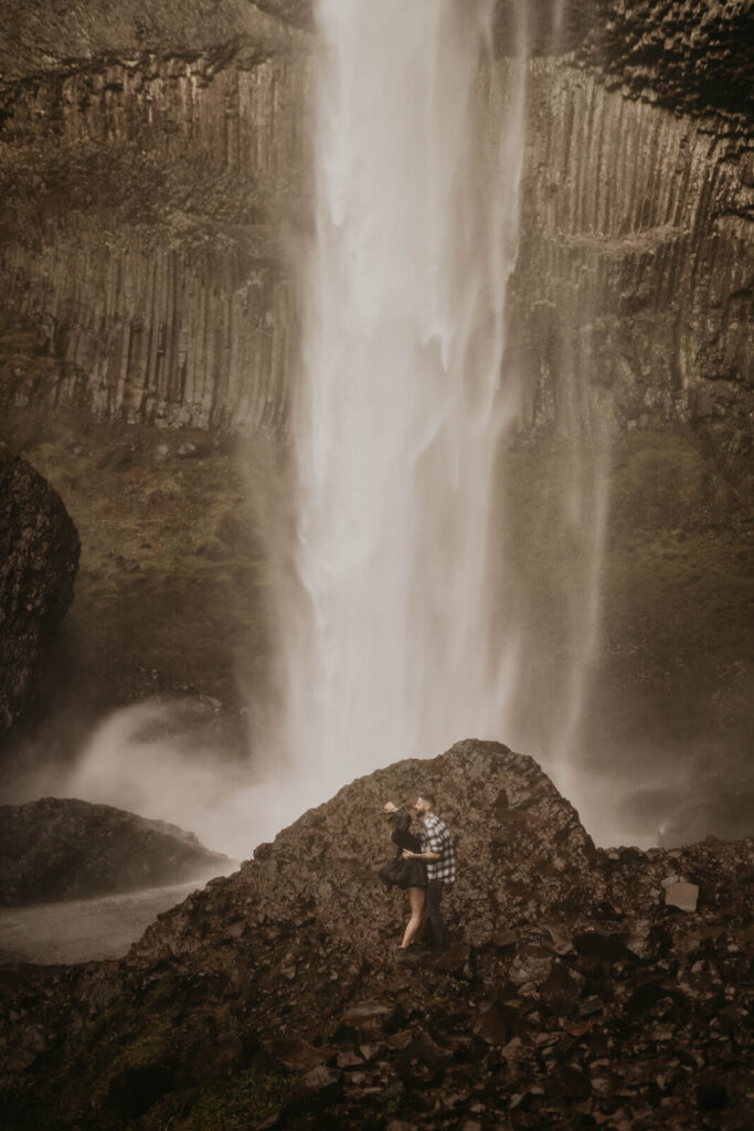 Couple kissing in front of Latourell Falls during their winter engagement photoshoot