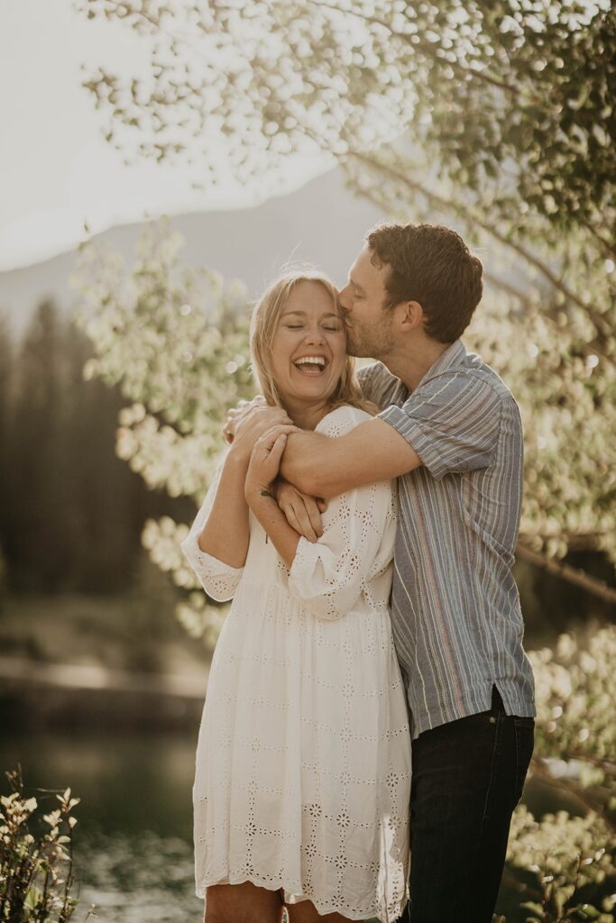 Man kissing woman on the head during destination engagement photos in Banff, Canada