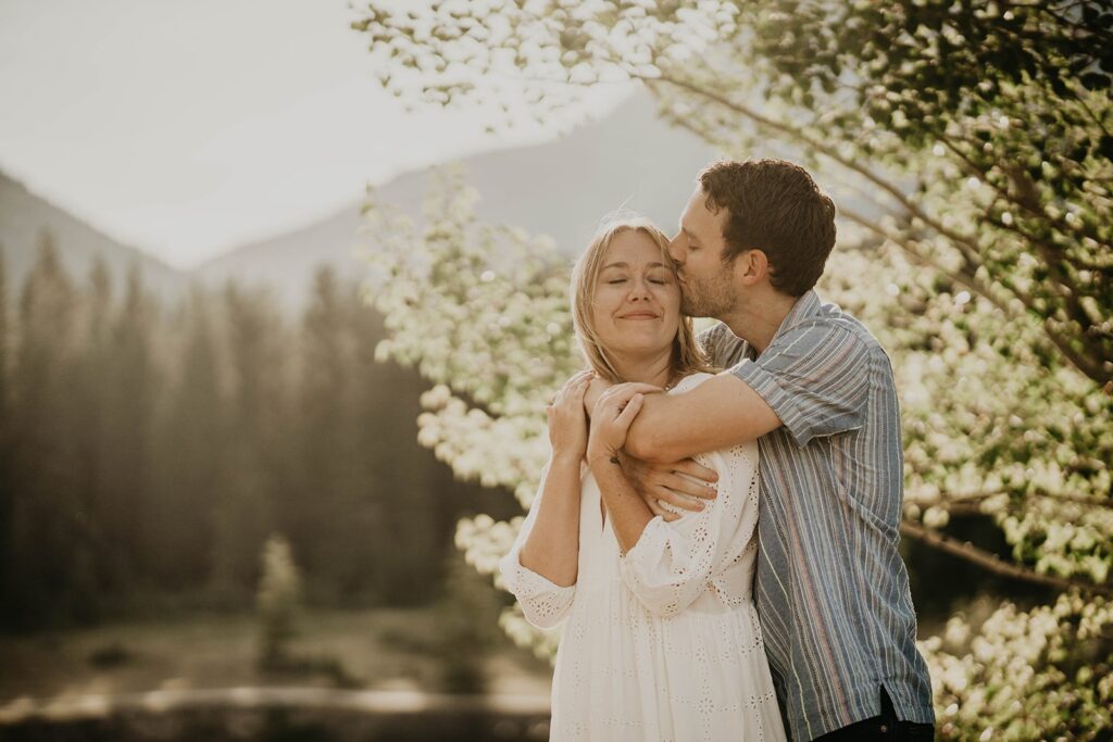 Man kissing woaman on the head during adventure engagement photos in Banff, Canada