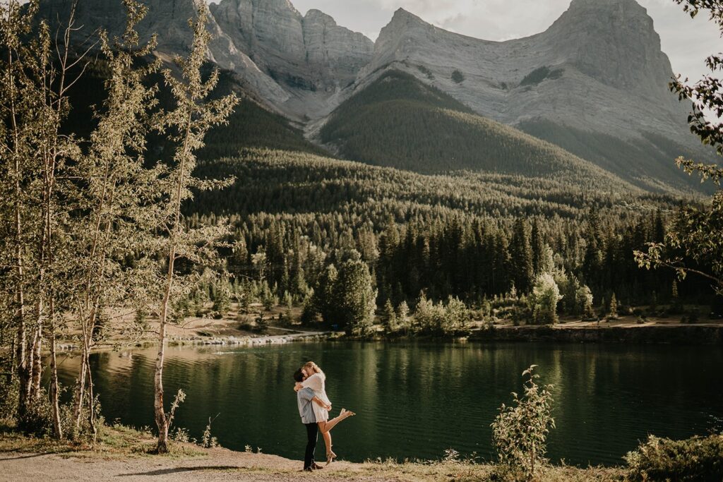 Man and woman kissing by the lake during summer engagement photos in Banff, Canada