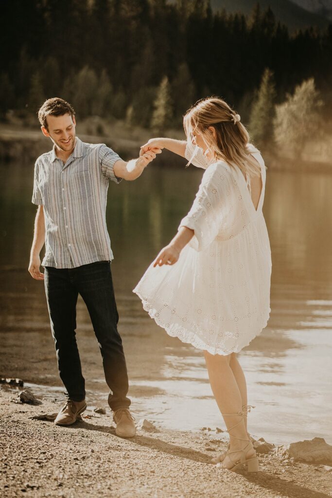 Man and woman dancing by the lake during summer engagement photos in Banff, Canada