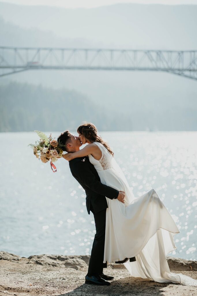 Bride and groom kissing during Thunder Island wedding portraits by the Columbia river