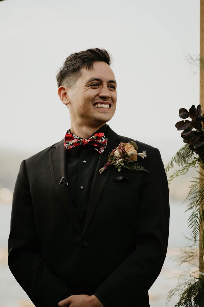 Groom smiling at bride as she enter fall wedding ceremony on Thunder Island